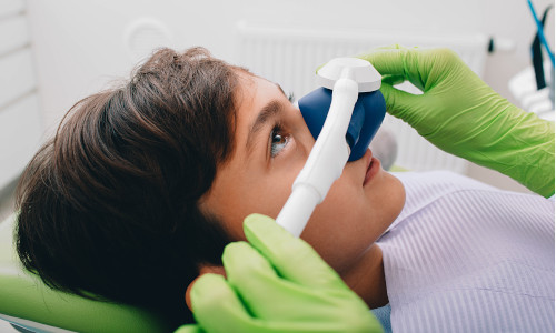 ein junde liegt auf dem behandlungsstuhl beim zahnarzt mit einer lachgas maske auf seiner nase